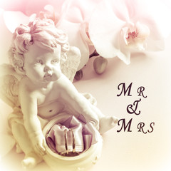 White Orchid angel sculpture wedding rings on pink background. Mr and Mrs