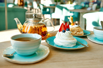 meringue with cream and strawberries with a cup of tea, teapot in the cafe