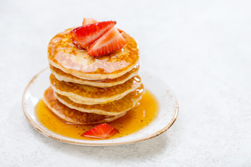 Homemade pancakes with strawberries on a light background with copy space.
