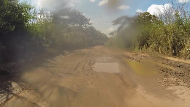 POV offroad drive on muddy wet African track in Angola with lots of water spray and mud holes