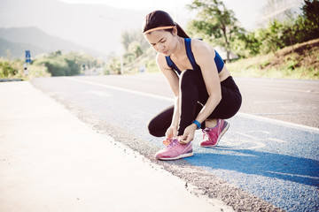 young woman runner tying shoelaces