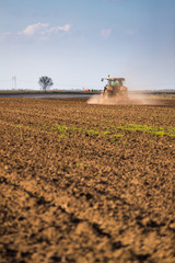 Fototapeta premium Farmer in tractor preparing land with seedbed cultivator as part of pre seeding activities in early spring season of agricultural works at farmlands.