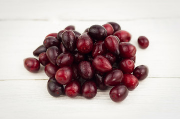 Heap of red fresh raw cornel on old white wooden rustic table