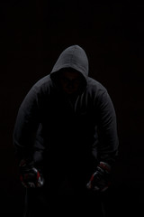 Male adult with black hoodie on black background. High resolution image concept for boxing and fighting industry.