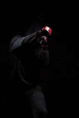 Fototapeta na wymiar Male adult with black hoodie on black background. High resolution image concept for boxing and fighting industry.