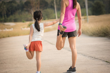 mother and her daughter doing stretching exercises on the road in the countryside, sports, healthy...