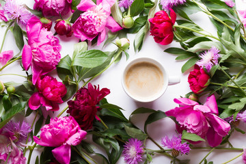 Morning coffee and beautiful pink and red peony flowers on white table top view in flat lay style. Cozy breakfast on Mother or Woman day.