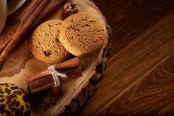 Christmas still life with assortment of cookies, cinnamon and dried oranges on a log, close-up, selective focus.