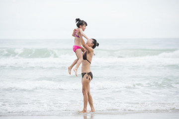 Mother and daughter walking on the beach.