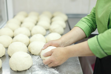 the cook kneads pieces of dough lying on the steel table top. horizontal frame. Only hands and dough in the frame