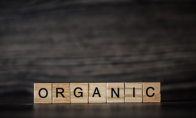 the word organic, consisting of light wooden square panels on a dark wooden background