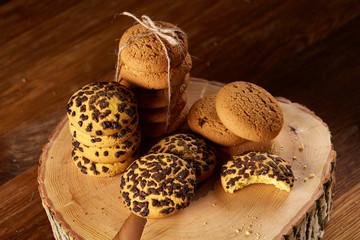 Sweet assortment of biscuits on a round wood log over rustic wooden background, close-up, selective focus.