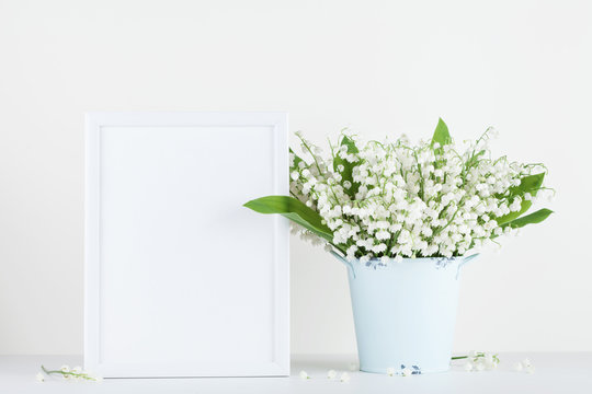Mockup of picture frame decorated flowers in vase on white background with clean space.