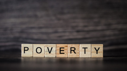 the word poverty made up of light wooden planks on a dark wooden background