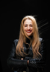 Photo of smiling blonde in leather jacket with arms crossed at waist