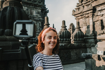 Young tourist woman takin pictures of the amazing Candi Prambanan or Rara Jonggrang, largest Hindu temple site in Indonesia. Yogyakarta, Java. Travel photography.