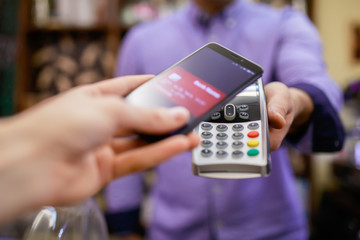 Image of buyer pays with smartphone near seller man with terminal