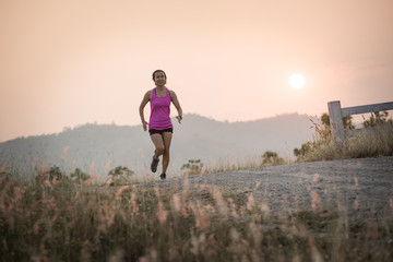 Young lady running on a rural road during sunset, sports, healthy lifestyle