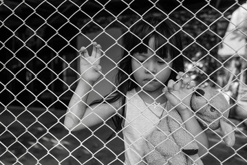 The sad Asian girl child, while sitting alone in cage was imprisoned make no freedom or lack of freedom
