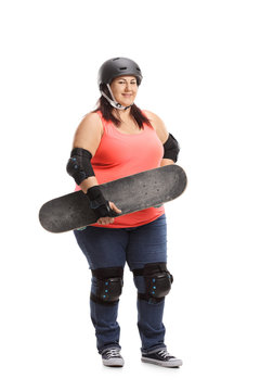 Overweight woman wearing protective gear holding a skateboard