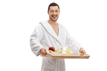 Young man in a bathrobe holding a breakfast tray