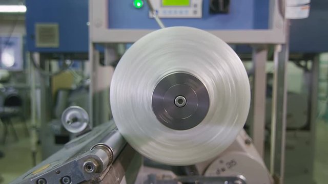 closeup threads wind on rotating bobbin in factory