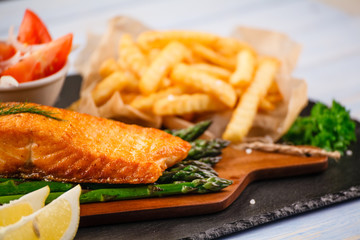 Fried salmon with french fries on wooden table