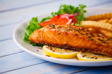 Fried salmon with french fries on wooden table