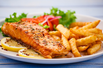 Fried salmon with french fries on wooden table