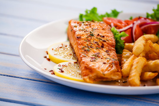 Fried salmon with french fries on wooden table