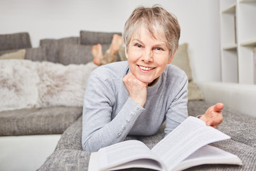 Seniorin mit einem Buch auf der Couch