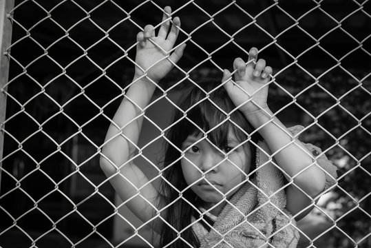 The sad Asian girl child, while sitting alone in cage was imprisoned make no freedom or lack of freedom