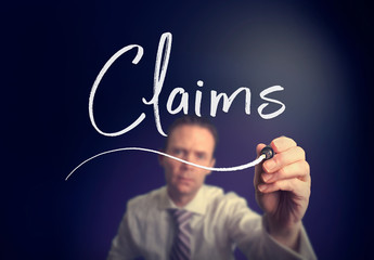 A businessman writing a Claims concept with a white pen on a clear screen.