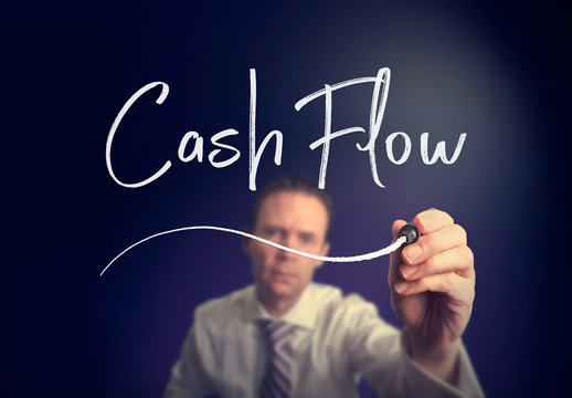 A businessman writing a Cash Flow concept with a white pen on a clear screen.