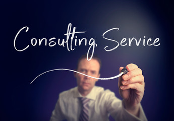 A businessman writing a Consulting Service concept with a white pen on a clear screen.