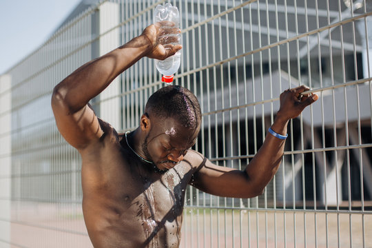 Seductive African American man with muscels poses with naked chest before the fence