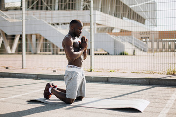 Man does meditation during his morning work out outside on the street