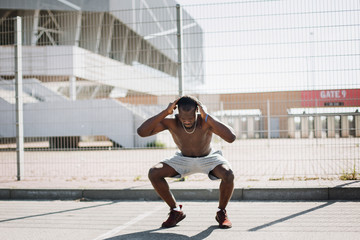 African American man does squats during the fitness work out on the street