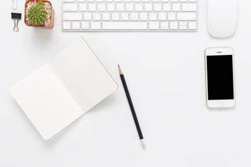 Top view, empty notebook with smartphone and computer and office supplies on white office desk