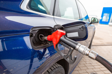 Fuelling gun inserted into the tank of blue car