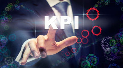 A businessman pressing a KPI business concept on a graphical display of cogs