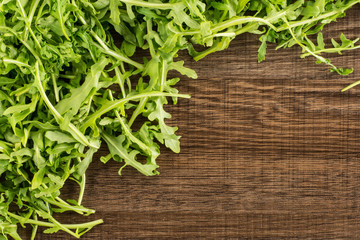 Fresh arugula leaves flatlay isolated on brown wood background.
