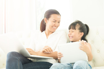 mother with daughter looking at Laptop  on sofa