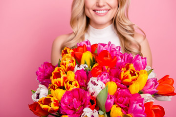 Cropped portrait of half face pretty wife charming girlfriend positive mother with beaming smile holding colorful big bouquet of tulips in hands isolated on pink background