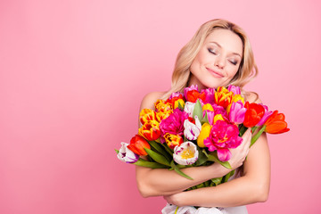 Obraz na płótnie Canvas Portrait with copy space, empty place of pretty cute lovely woman with close eyes having big colorful aromatic bouquet of tulips in hands isolated on pink background