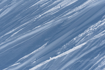 Multiple wind packed snow ridges forming oblique lines in sunshine