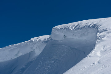 Windblown curved snow ridge in winter sunshine