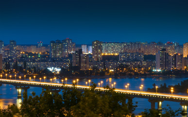 Fototapeta na wymiar Night Kiev cityscape. Kyiv Left bank skyline with Paton bridge over Dnieper river