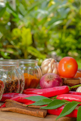 Curry powder, chili powder, tomato, curry leaves,  cinnamon, garlic, onion, chili, and herbs on an old table. Concept cuisine Asian countries