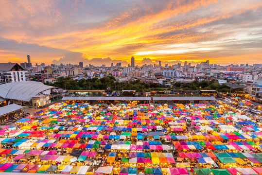 Top view of outdoor night market with Bangkok cityscape i n background under twilight evening sky and night light in Bangkok, Thailand